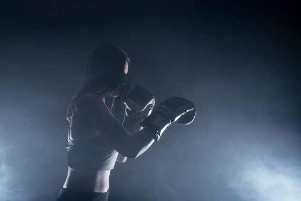 侧视图的剪影，一个年轻的女人与拳击手套直接击中。图片下载