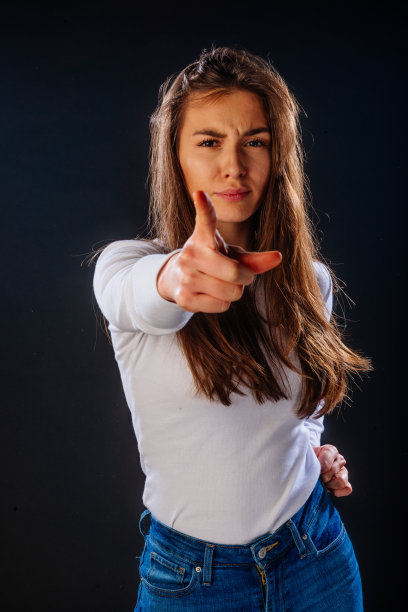 英俊的女模特指着你，而站在一个黑色的背景前图片下载