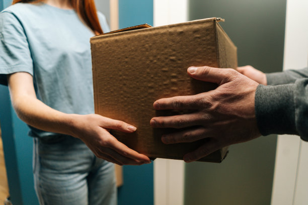 特写镜头的女性客户收到纸箱包裹在家里从送货员的手在台阶上。图片下载