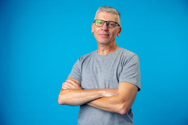 老年男子的肖像与手臂交叉在蓝色背景图片下载