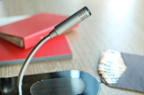 贿赂、腐败或黑钱的概念:在会议室的桌子上，一个麦克风与对讲机的特写镜头，里面有文件和文件夹，背景是一个装有几张50欧元钞票的信封图片下载