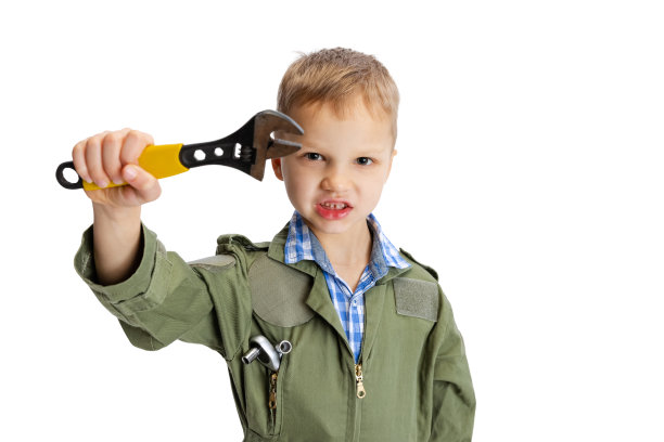 一个情绪激动的小男孩，可爱的小男孩，穿着绿色工装裤的汽车修理工或装配工，工作工具被隔离在白色的工作室背景上。童年,教育理念图片下载