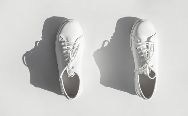 白色妇女的皮革运动鞋与日光阴影在白色背景上的顶视图。时尚的青年运动鞋、运动鞋、真皮皮鞋。简约的鞋店广告时尚风格图片下载