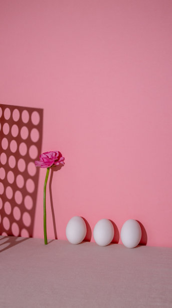 垂直的照片。鸡蛋和粉色花朵的简约构图。背景是亮粉色的。复活节的概念,明信片图片下载