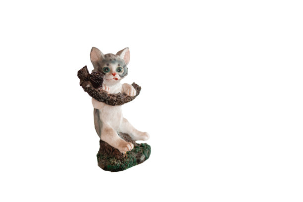 一个陶瓷雕像，一只猫爬在一个有蛋的窝的树枝上。舔猫孤立在白色的背景上图片下载