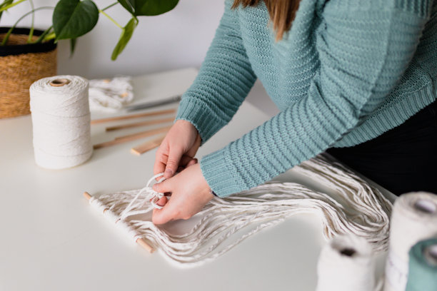 女人做流苏时的手。天然棉线和木珠。手工编织腰带在工作过程中。女性的爱好。图片下载