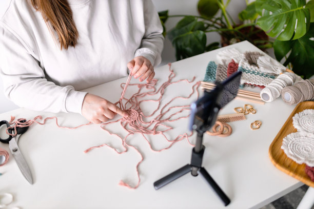 女人在客厅录制新的视频日志。把智能手机放在三脚架上，女孩做在线直播，引领网络远程聊天，现代科技，视频概念。手工编结。女性的爱好图片下载