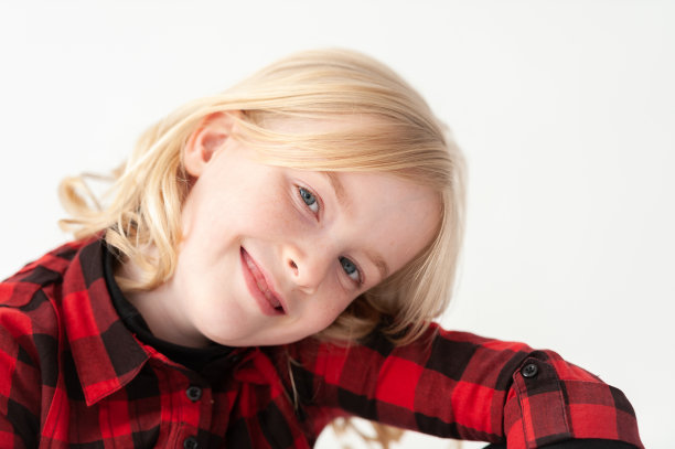 在工作室的白色背景下，一个十几岁的金发小女孩的头以一个角度翘起图片下载