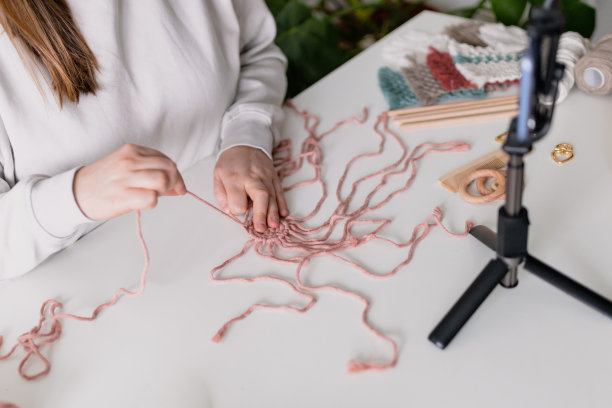 女人在客厅录制新的视频日志。把智能手机放在三脚架上，女孩做在线直播，引领网络远程聊天，现代科技，视频概念。手工编结。女性的爱好图片下载