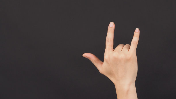 “我爱你”的手势。在黑色背景上做右手反手。图片下载