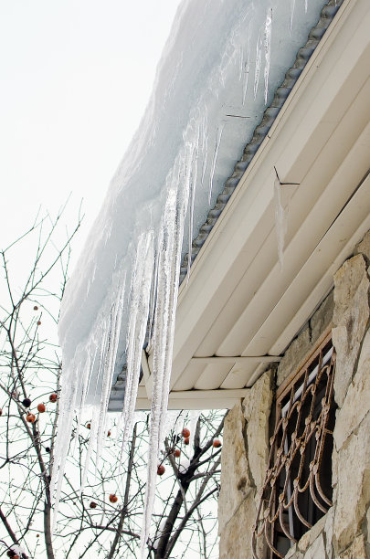 危险的冰柱从屋顶落下。垂直的摄影。图片下载