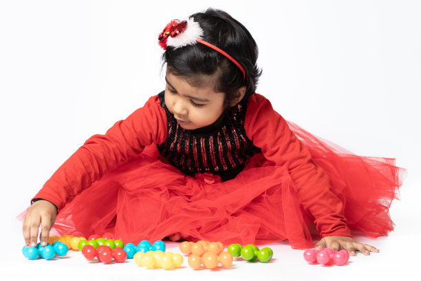 快乐的印度漂亮女孩玩彩色玩具在白色的背景。趣味，活动，教育，幼儿园，生日，学习，家庭活动，学校，托儿所，日托，发展理念图片下载