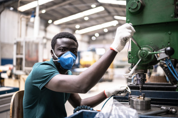 一名年轻男子在工厂/工业中工作——戴着口罩图片下载