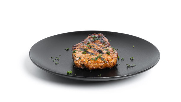 酱汁猪肉排放在盘子上，白色背景图片下载