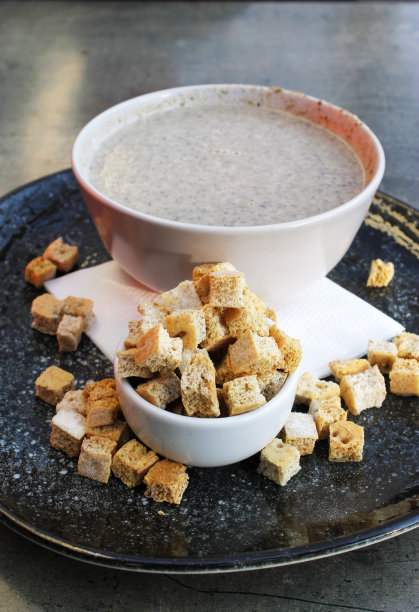 美丽的特写照片美味的蘑菇汤碗与面包块在一个黑色的盘子图片下载