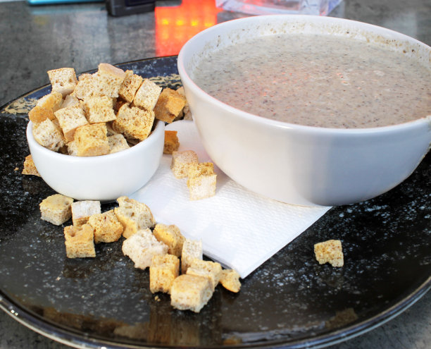 美丽的特写照片美味的蘑菇汤碗与面包块在一个黑色的盘子图片下载