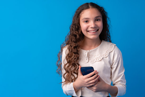 小女孩用手机。在蓝色背景下图片下载