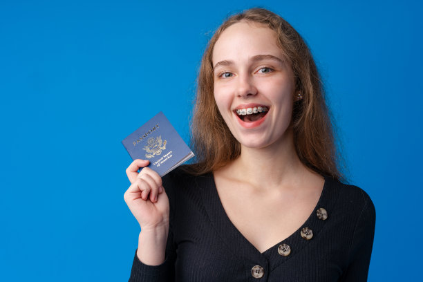 一个十几岁的女孩拿着一本蓝色背景的护照图片下载