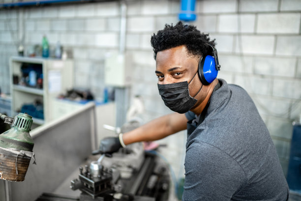 一名中年男子在工厂/工业中工作-戴着防护口罩图片下载