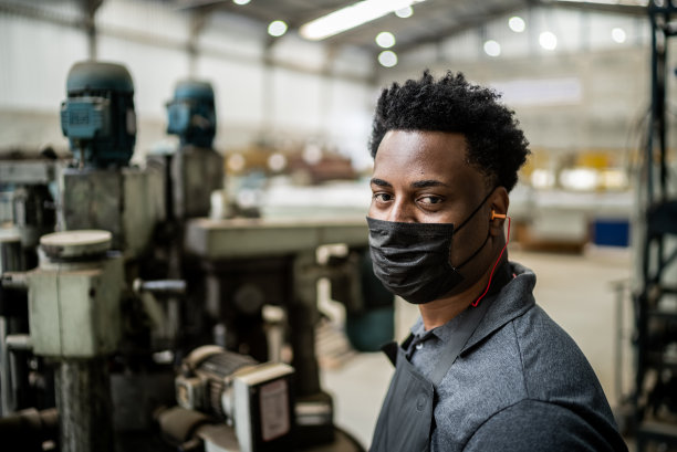 一名中年男子在工厂/工业中工作-戴着防护口罩图片下载