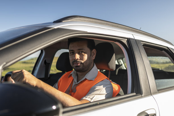 带着防护设备的电气工程师坐在一辆移动的车里前往风力发电厂。图片下载
