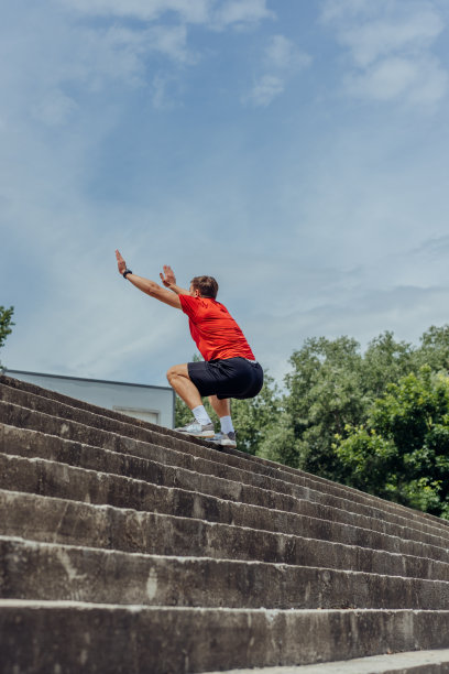 一名活跃的男性运动员在户外训练中跳上楼梯的侧面照片。图片下载