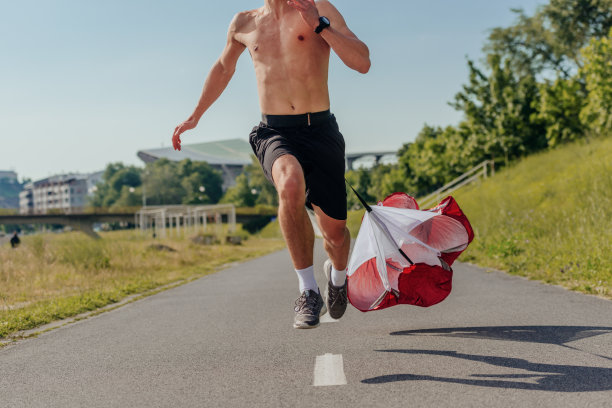 一个英俊的运动员腰上绑着阻力降落伞跑步的特写照片图片下载