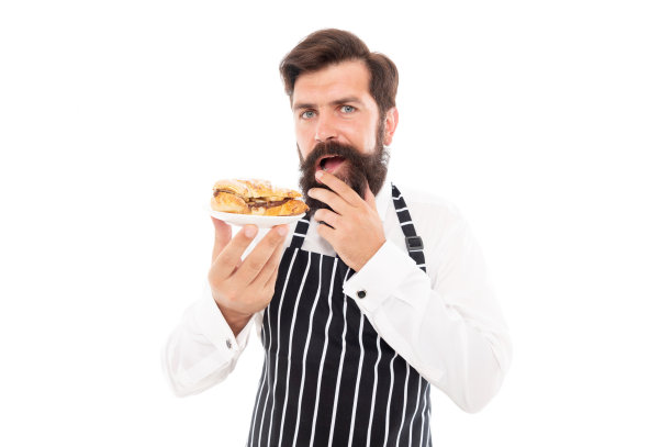 严肃的男人面包师提供美味的羊角面包和白色甜点图片下载