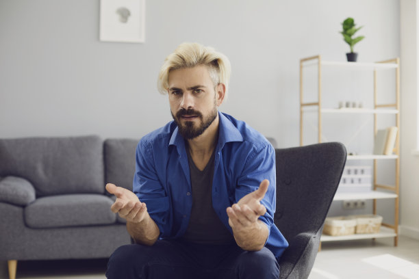 困惑的潮人坐在家里的扶手椅上图片下载