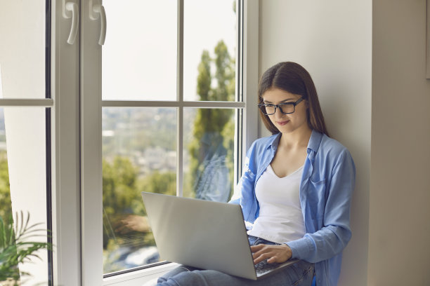 在家工作。小女孩坐在窗台上用笔记本电脑和老板进行网络视频通话或网络会议图片下载