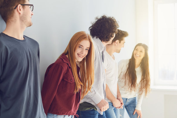 一群微笑的朋友站在一间有窗的明亮房间里。图片下载