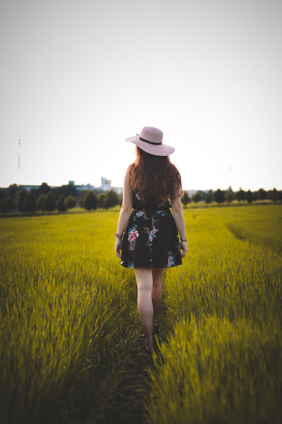 一个年轻的女人穿着花裙子，穿过贝斯基山脉附近的绿色田野。一个漂亮女人梳理头发的率直肖像。天真快乐的表情图片下载