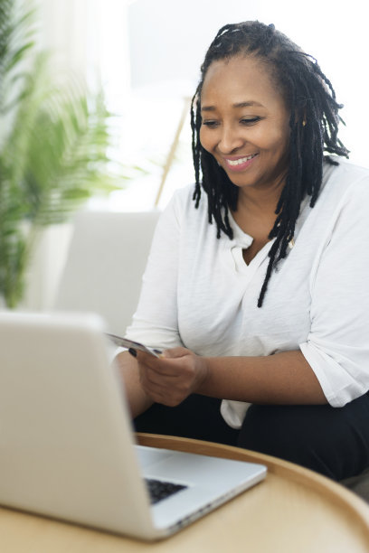 漂亮的黑人女人用笔记本电脑在家里的沙发上买东西的照片图片下载