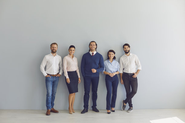 一组快乐的商人站在办公室墙壁旁看着相机的照片图片下载