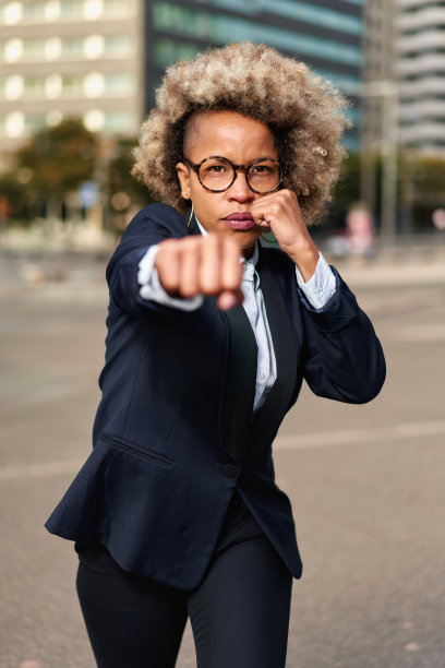 强硬的竞争经营理念。非裔美国妇女举起拳头摆出战斗姿势。图片下载