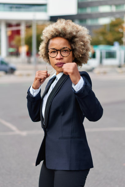 强硬的竞争经营理念。非裔美国妇女举起拳头摆出战斗姿势。图片下载