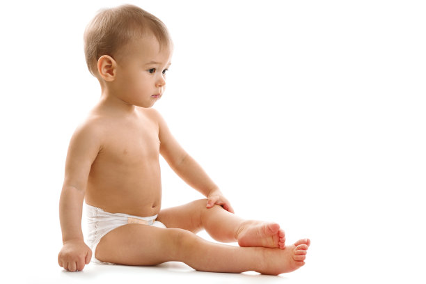 好奇的健康小男孩穿着尿布坐着看。图片下载