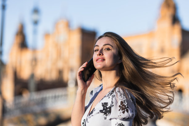 时尚的女人在街上打电话，头发在风中飘图片下载