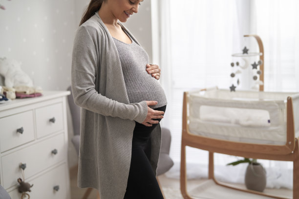愉快的白人妇女在怀孕晚期站在婴儿房，等不及要孩子图片下载
