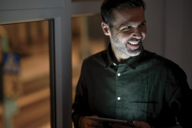 成年白人男子在办公室使用数码平板电脑，目光移开图片下载