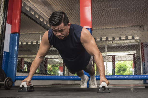 一个健康的亚洲男人在综合格斗馆用俯卧撑做宽的俯卧撑。体重健美操或HIIT锻炼。训练胸部，肩膀，核心肌和三头肌。图片下载