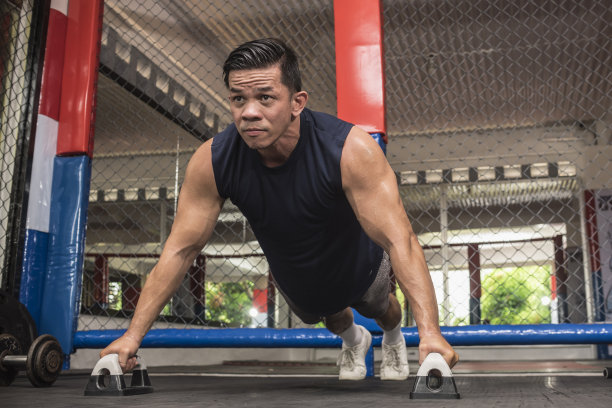 一个健康的亚洲男人在综合格斗馆用俯卧撑做宽的俯卧撑。体重健美操或HIIT锻炼。训练胸部，肩膀，核心肌和三头肌。图片下载