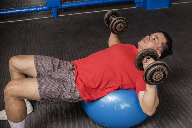 一个健康和运动的亚洲人做瑞士球哑铃胸压。在健身房锻炼。图片下载