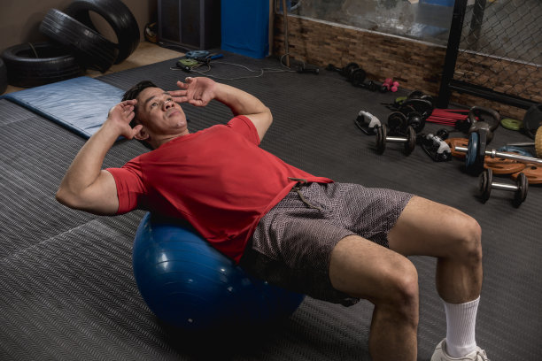 一个运动员和健康的亚洲人做仰卧起坐或仰卧起坐的稳定球。腹肌和核心肌群锻炼。图片下载