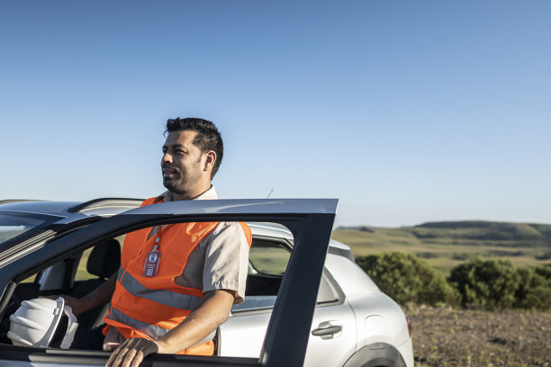 一个带着防护设备的电气工程师从一辆电动汽车里出来，在一个风电场公园里图片下载