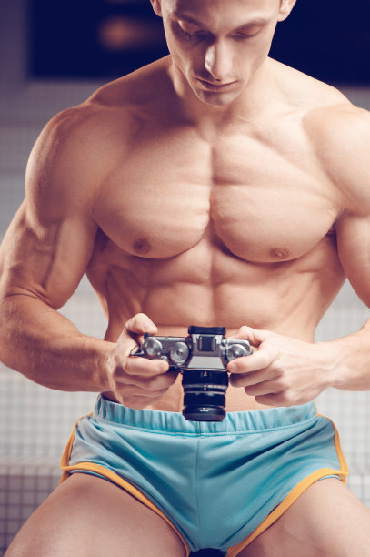 一个肌肉发达的年轻摄影师手里拿着一台老式相机图片下载