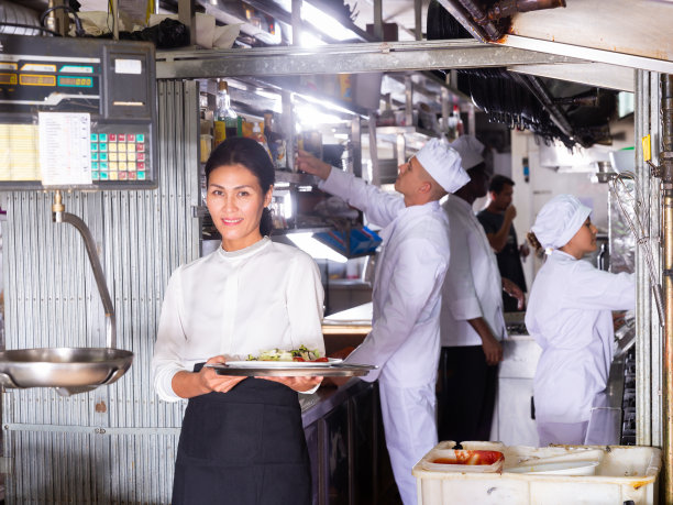 成功的女服务员站在餐厅厨房为客人点餐图片下载