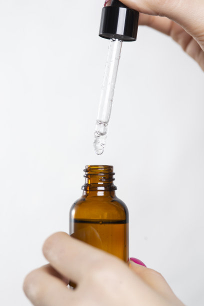 在白色背景上手持面部精华液。面部健康精华。抗衰老化妆品，提肤。棕色玻璃瓶中的血清。有机素食产品。文本的地方图片下载