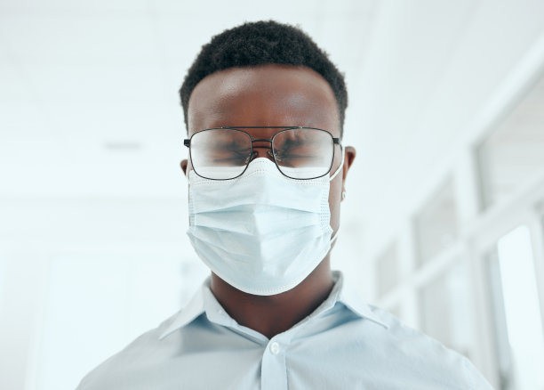 剪裁的镜头，一个英俊的年轻商人打喷嚏时，戴着口罩在办公室图片下载