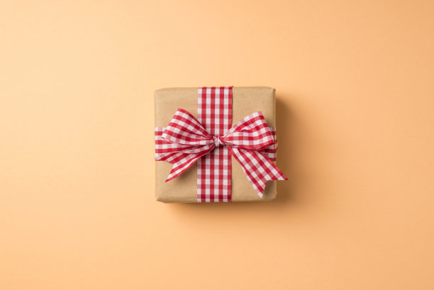 俯视图照片的情人节装饰牛皮纸礼盒与方格丝带蝴蝶结孤立的米色背景图片下载